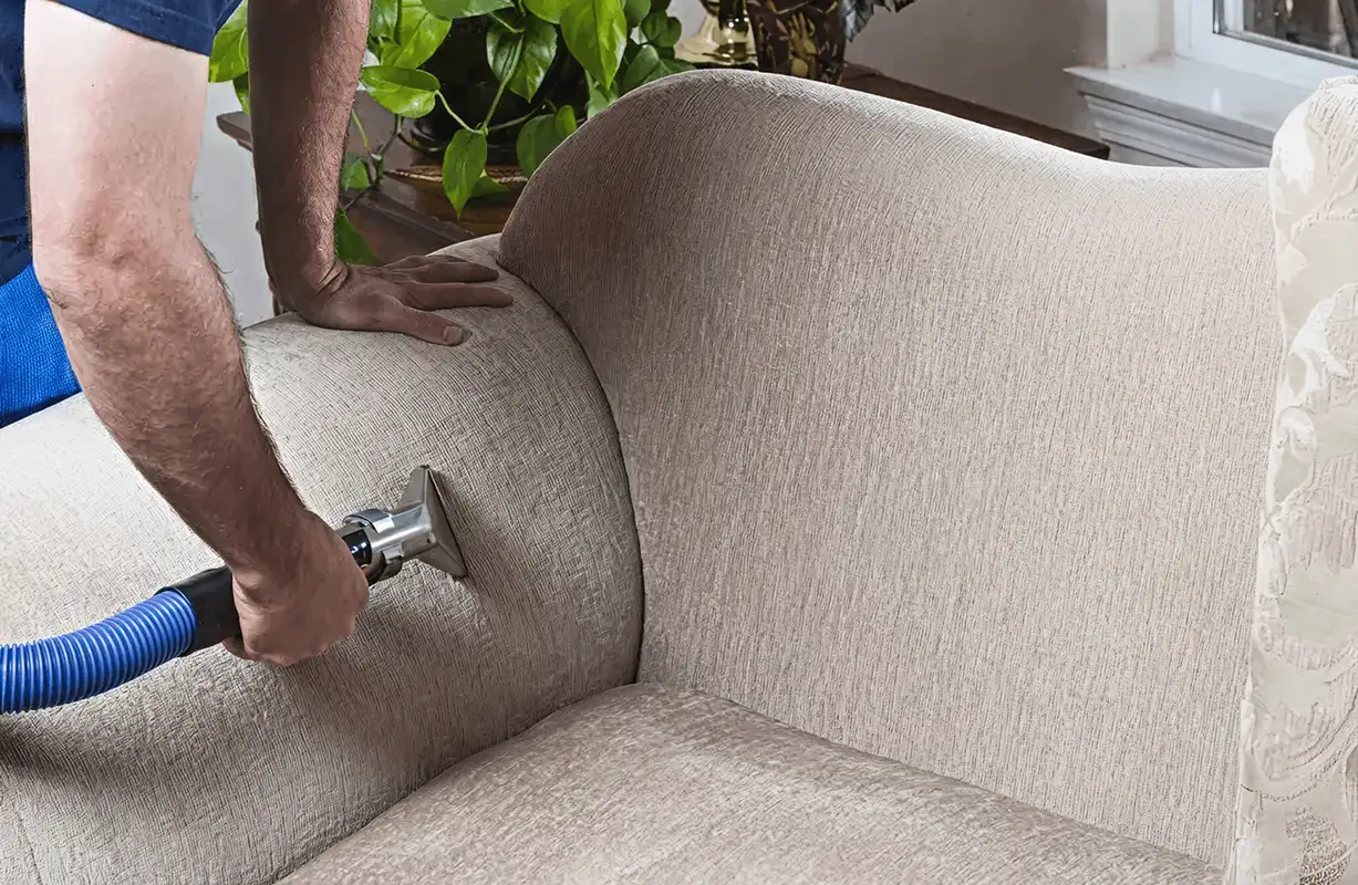 Professional upholstery cleaner deep-cleaning a fabric sofa with a handheld extraction tool and hose, Salt Lake City, UT.